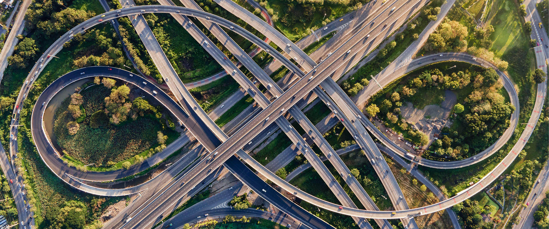 An aerial view of a road interchange or highway intersection with busy urban traffic speeding on the road | Bentley Systems | Infrastructure Engineering Software Company An aerial view of a road interchange or highway intersection with busy urban traffic speeding on the road
