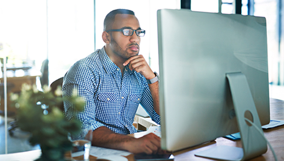 A man sitting at a desk in front of a computer, giving a demo. | Bentley Systems | Infrastructure Engineering Software Company A man sitting at a desk in front of a computer, giving a demo.