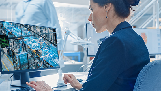 A woman is demoing a computer in a factory. | Bentley Systems | Infrastructure Engineering Software Company A woman is demoing a computer in a factory.